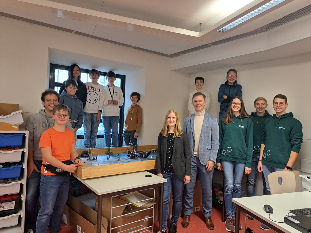 Die Robotik-FLL-Gruppe mit den Dualstudierenden, Kursleiter, Schulleiter und Frau Feil von Infineon